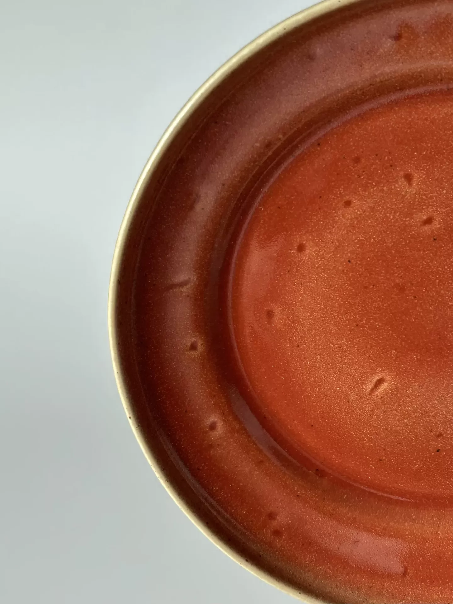 Prato de cerâmica castanho-avermelhado com borda bege e textura irregular.