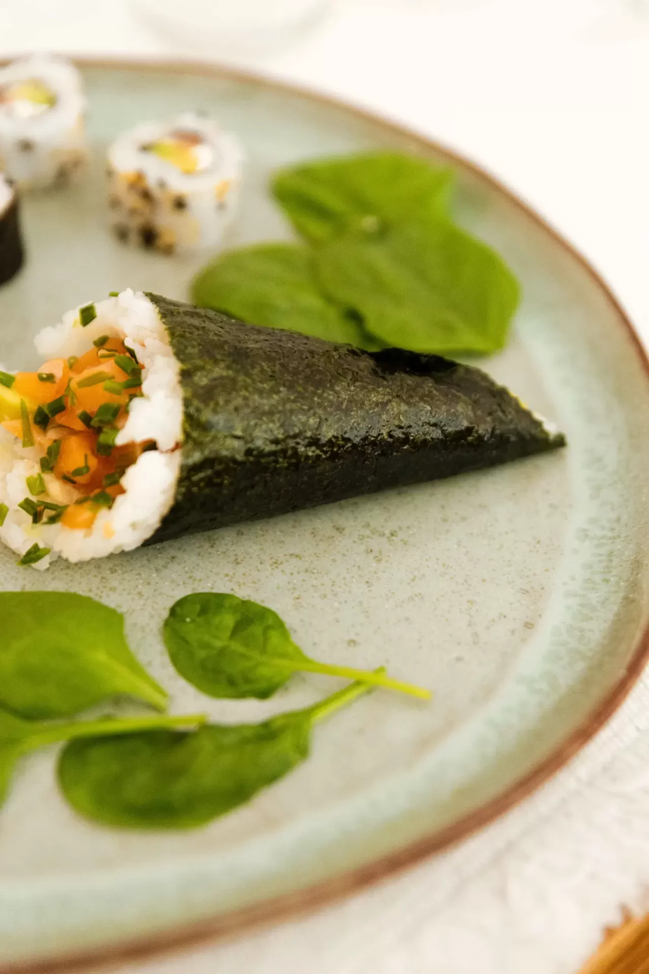 Prato com sushi de arroz e alga com recheio colorido e folhas verdes