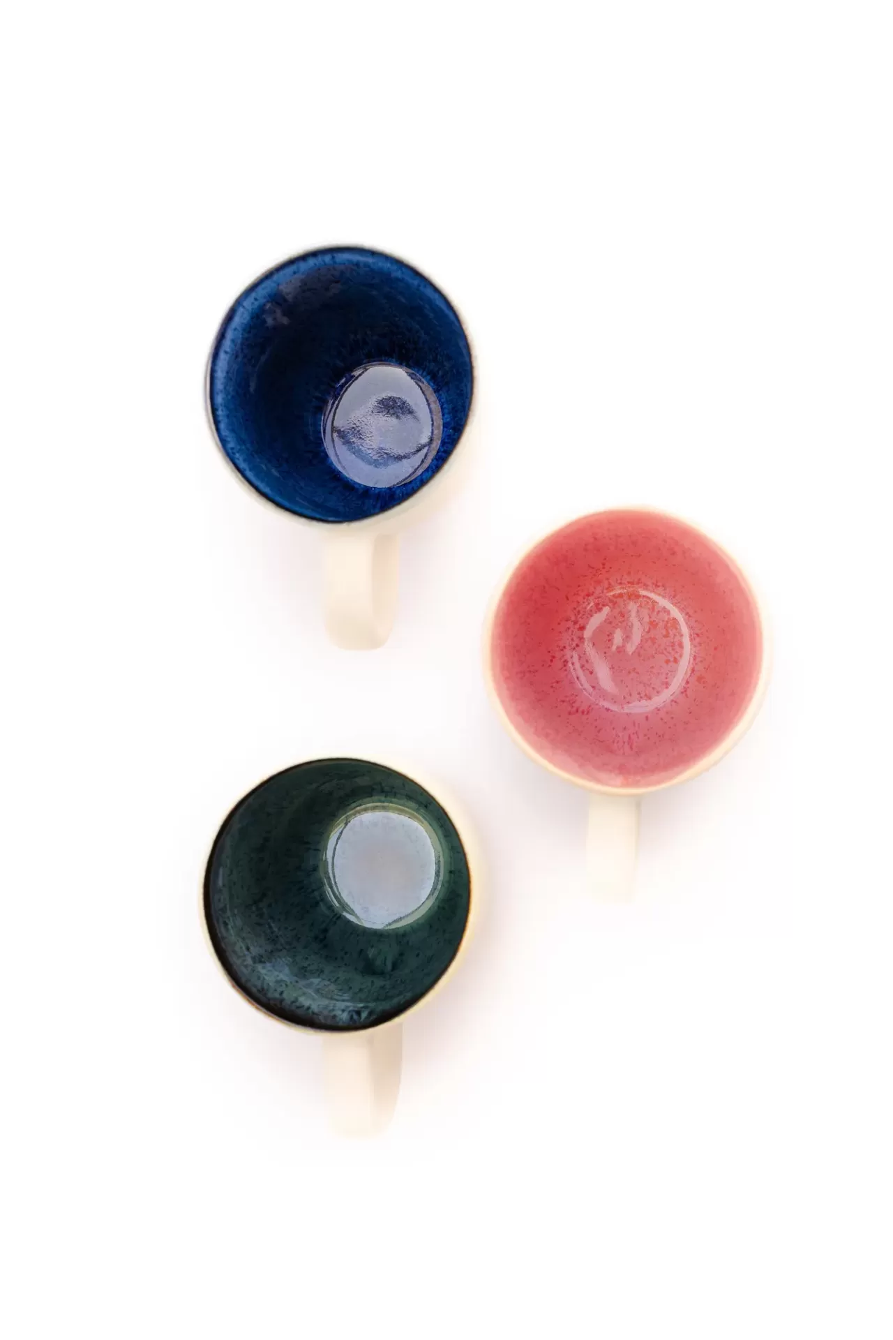 Três chávenas de cerâmica coloridas vistas de cima.