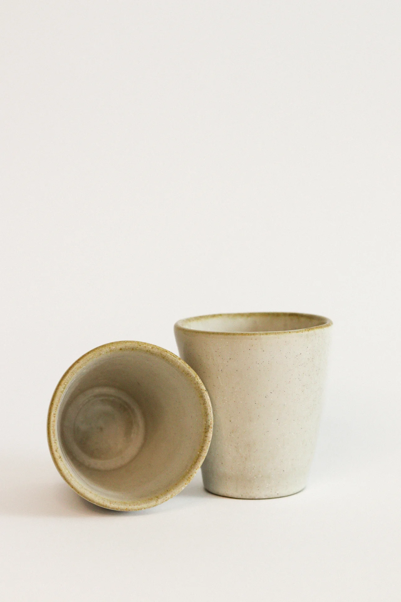 Duas chávenas de cerâmica bege com textura sobre fundo branco