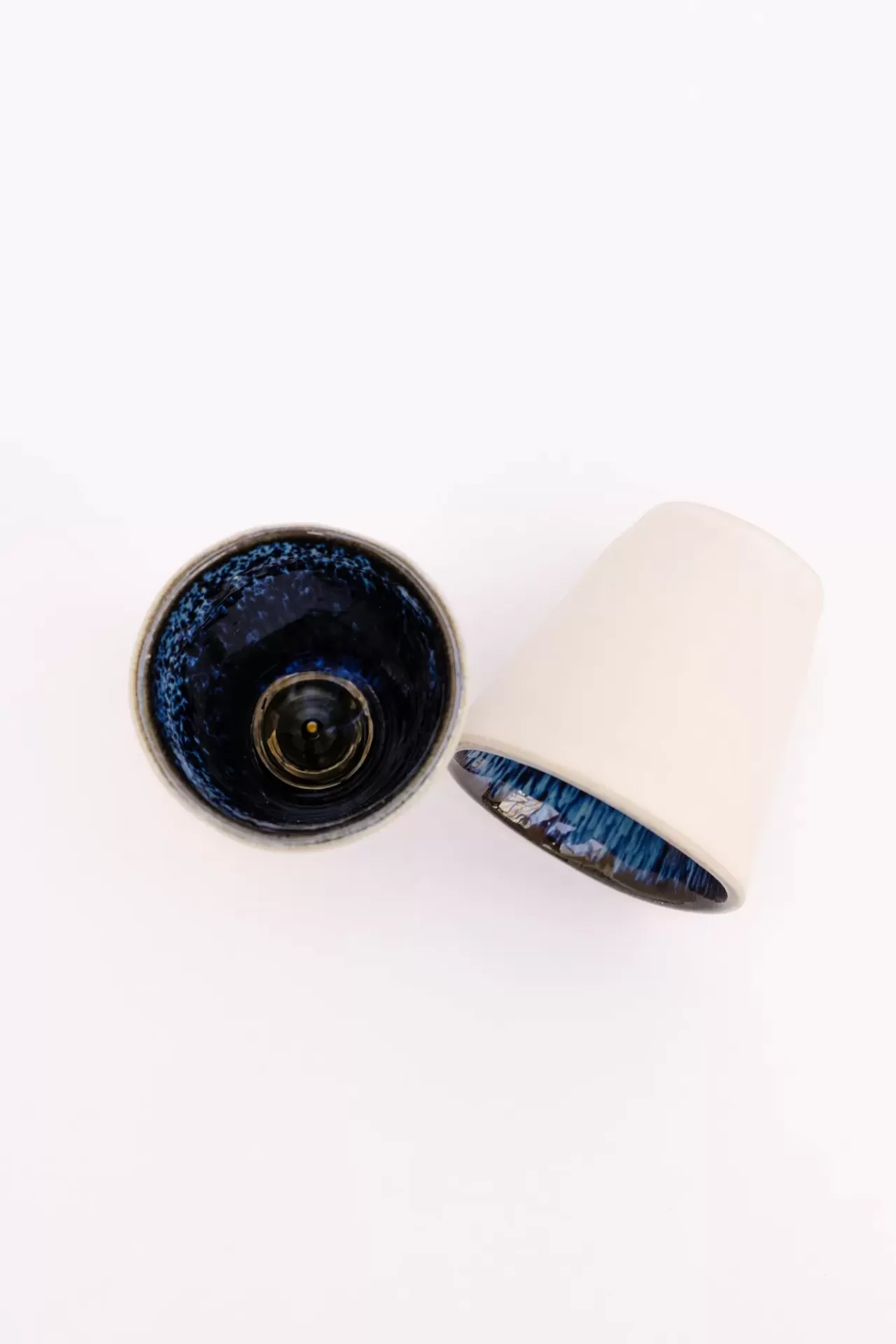 Dois copos brancos com interior azul, vistos de cima sobre fundo branco.