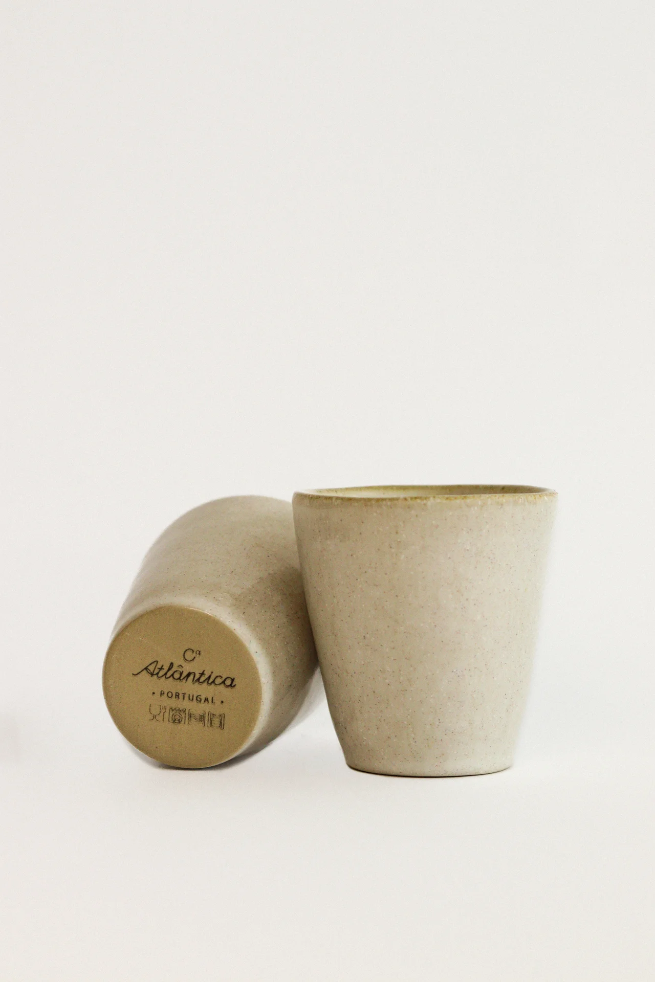 Dois copos de cerâmica bege com texto Atlântica PORTUGAL na base