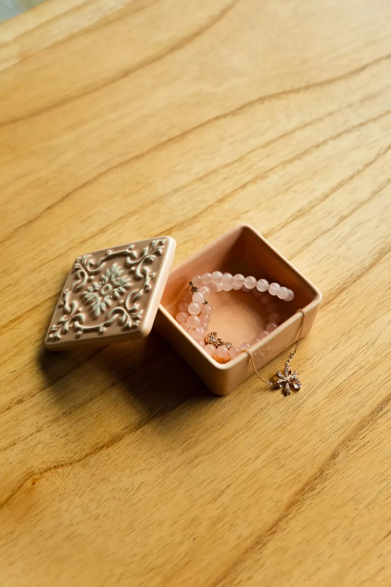 Caixa de cerâmica com pulseira de contas rosa e colar dourado com pendente em flor