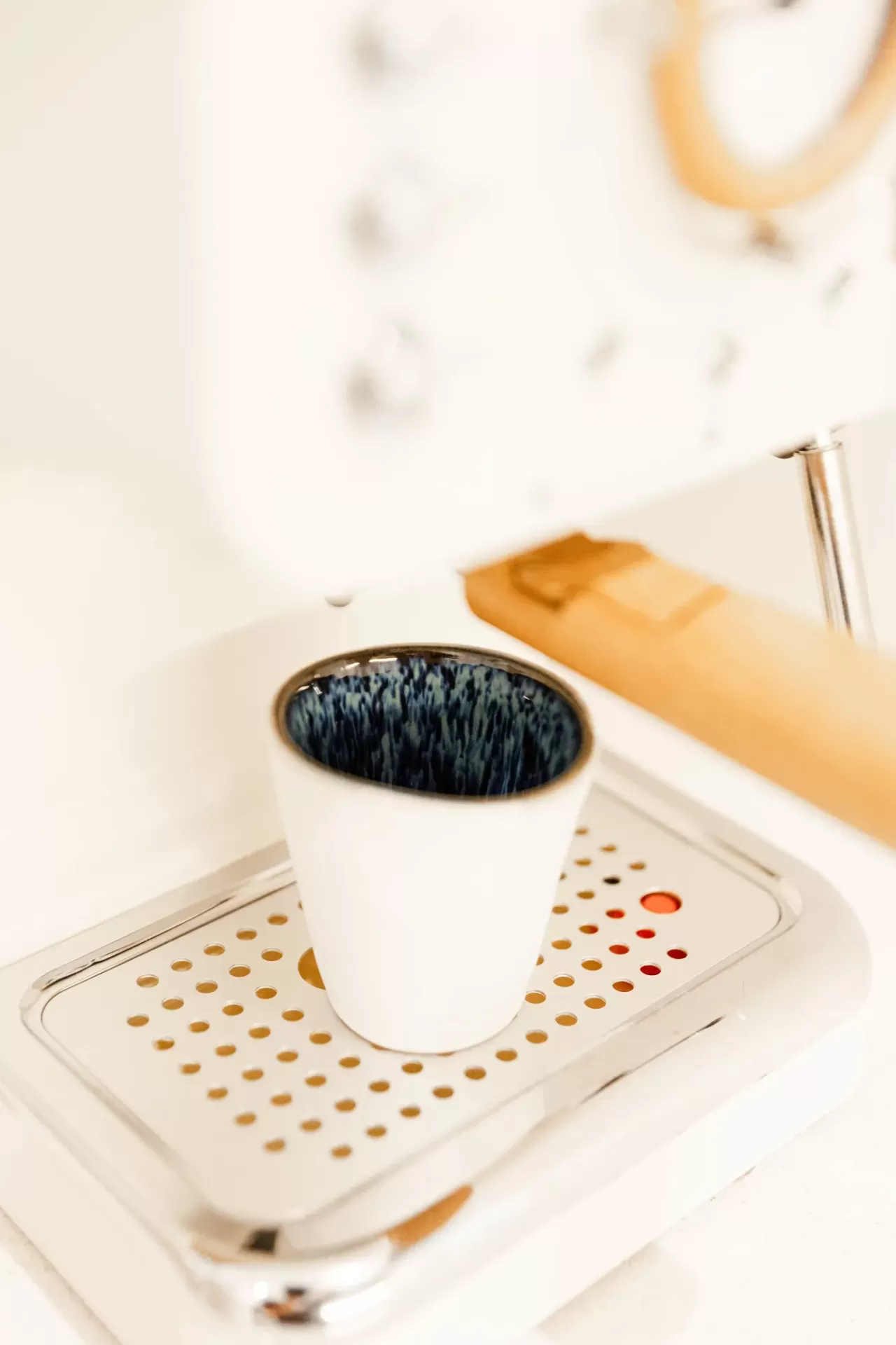 Copo de cerâmica branca a receber café de máquina de café branca com detalhes em madeira