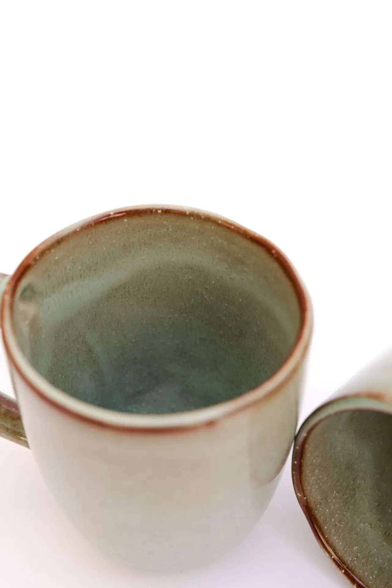 Caneca de cerâmica cinza esverdeada com borda castanha e pires correspondente