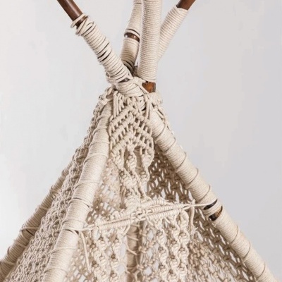 Estrutura de barraca com paus de madeira e tecido macramé bege em fundo branco