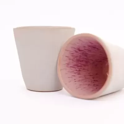 Duas chávenas cerâmicas branca e rosa sobre fundo branco