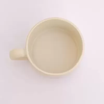 Caneca de cerâmica bege vista de cima sobre fundo branco