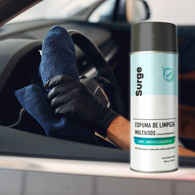 Spray de espuma de limpeza da marca Surge e mão a limpar interior de carro com pano azul