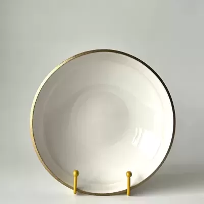 Prato redondo branco com borda dourada em suporte amarelo