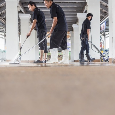 Três homens a limpar chão em estrutura com colunas brancas