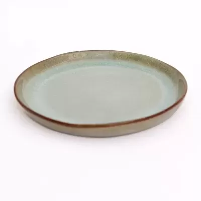 Prato redondo de cerâmica azul e castanho sobre fundo branco