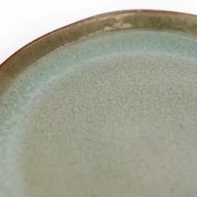 Prato de cerâmica verde com textura craquelada e borda irregular.