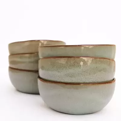 Seis tigelas de cerâmica verde com bordas castanhas empilhadas em duas pilhas