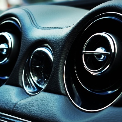 Saídas de ar redondas em painel de carro preto com detalhes cromados