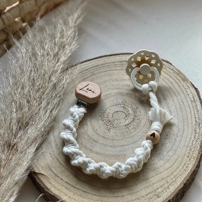 Prendedor de chupeta branco com contas de madeira sobre disco de madeira