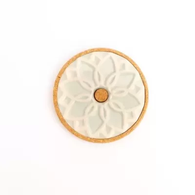 Suporte redondo em cortiça com placa de cerâmica branca e padrão floral em relevo