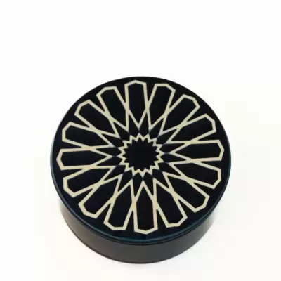 Caixa redonda preta com padrão geométrico creme na tampa