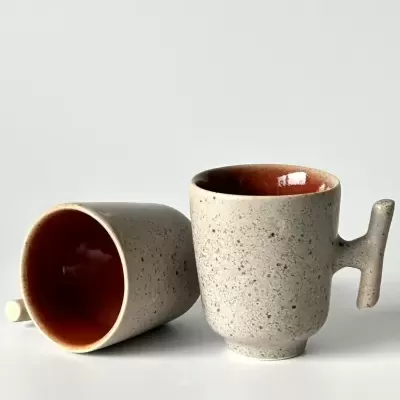 Dois copos de cerâmica cinza com interior castanho e pega distinta