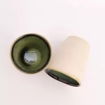 Dois copos cerâmicos bege com interior verde vistos de cima e de lado.