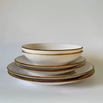 Conjunto de pratos brancos em cerâmica com bordas douradas empilhados