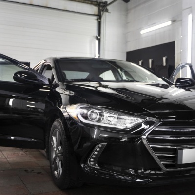 Carro preto com portas abertas dentro de garagem iluminação fluorescente