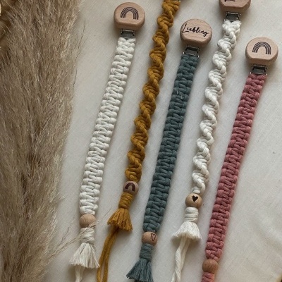 Cinco fitas trançadas de algodão com cabeças de madeira redondas com nomes e símbolos, em cores diversas