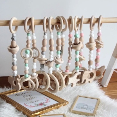 Brinquedos de madeira pendurados com contas coloridas pastel e quadros infantis no chão