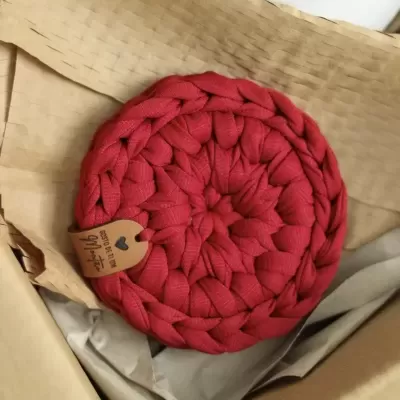 Tapete vermelho trançado em caixa de cartão com etiqueta de couro