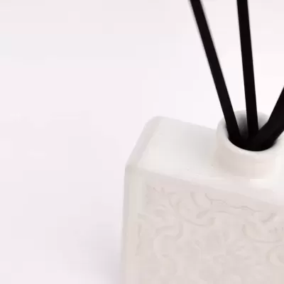 Recipiente branco com varetas pretas finas, difusor de aromas