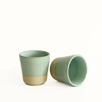 Dois copos de cerâmica verdes com base bege em fundo branco