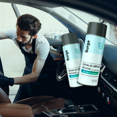 Frascos de espuma de limpeza Surge dentro de carro com interior castanho em couro e homem a limpar o assento.