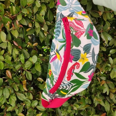 Necessaire floral colorida com fecho vermelho numa mão de manga verde.