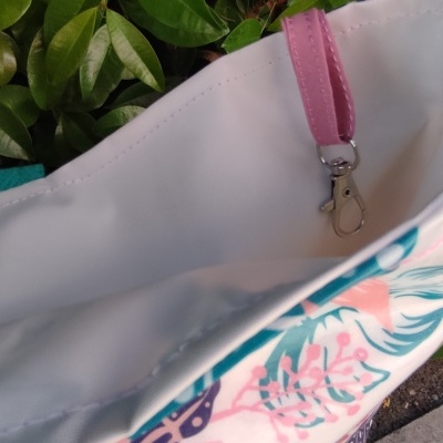 Sacola de tecido colorida com padrão de folhas e alça rosa