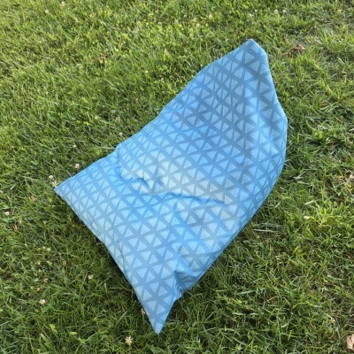 Almofada azul claro com padrão de triângulos brancos na relva verde
