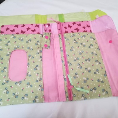 Estojo organizador aberto com tecido floral verde e rosa sobre superfície branca