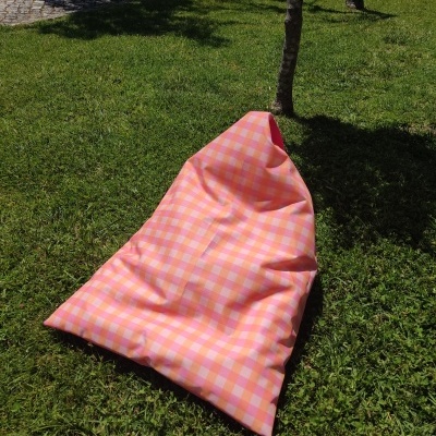 Pufe rosa com padrão às quadrículas em relva ao ar livre