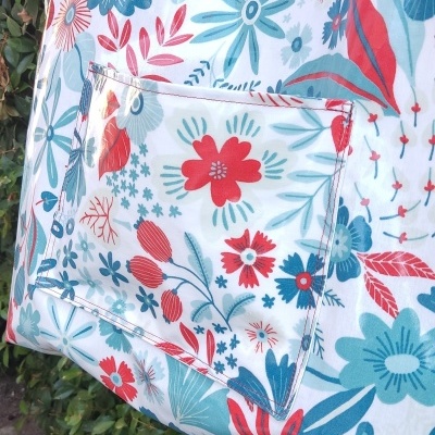 Bolsa de tecido floral com alças vermelhas e bolso frontal