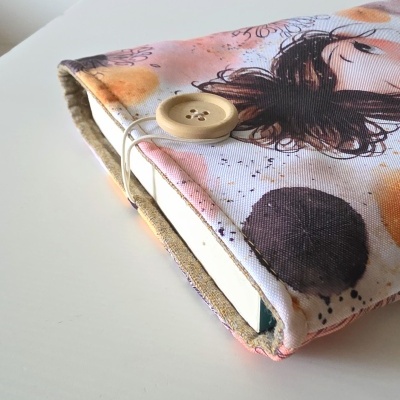 Capa de tecido com padrão abstrato e botão de madeira fechando.