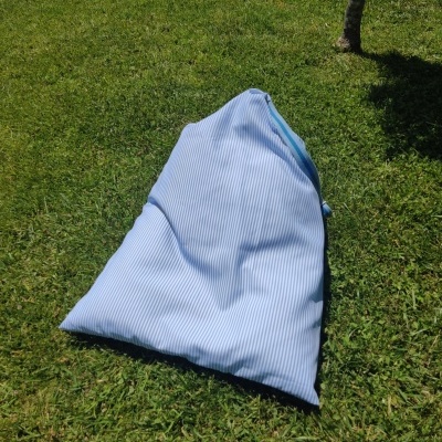 Pufe azul claro com riscas brancas sobre relva verde