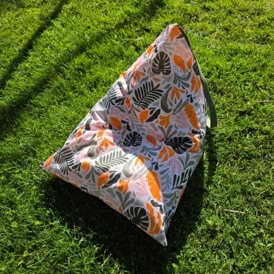 Pufe triangular com padrão colorido em relva verde