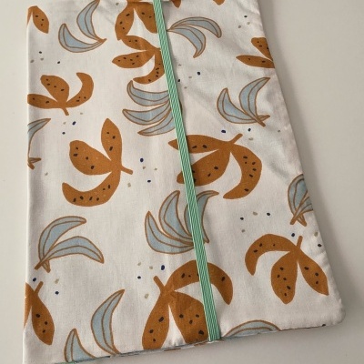 Capa de tecido para livro com estampado de folhas castanhas e azul clarinho e elástico verde claro