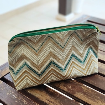 Estojo de tecido com padrão geométrico em ziguezague em bege, castanho, verde e branco com fecho verde