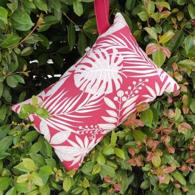 Almofada vermelha com folhas brancas pendurada em arbusto verde