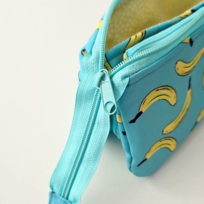 Necessaire azul clara com padrão de bananas e fecho de correr