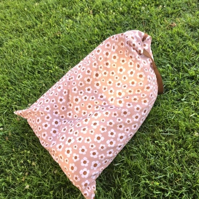 Pufe rosa com padrão de flores brancas em relva