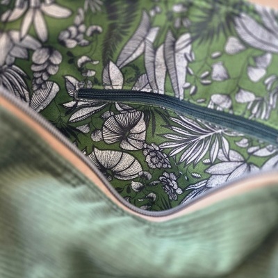Interior de mochila com padrão botânico verde e branco e fecho de correr azul escuro