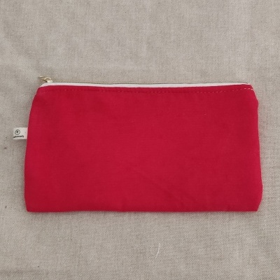 Estojo vermelho de tecido com fecho branco sobre tecido bege