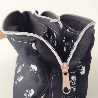 Bolsa preta com estampado de caveiras e fecho de correr prateado