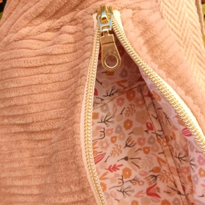 Mala rosa claro com fecho e interior floral junto a folhas verdes